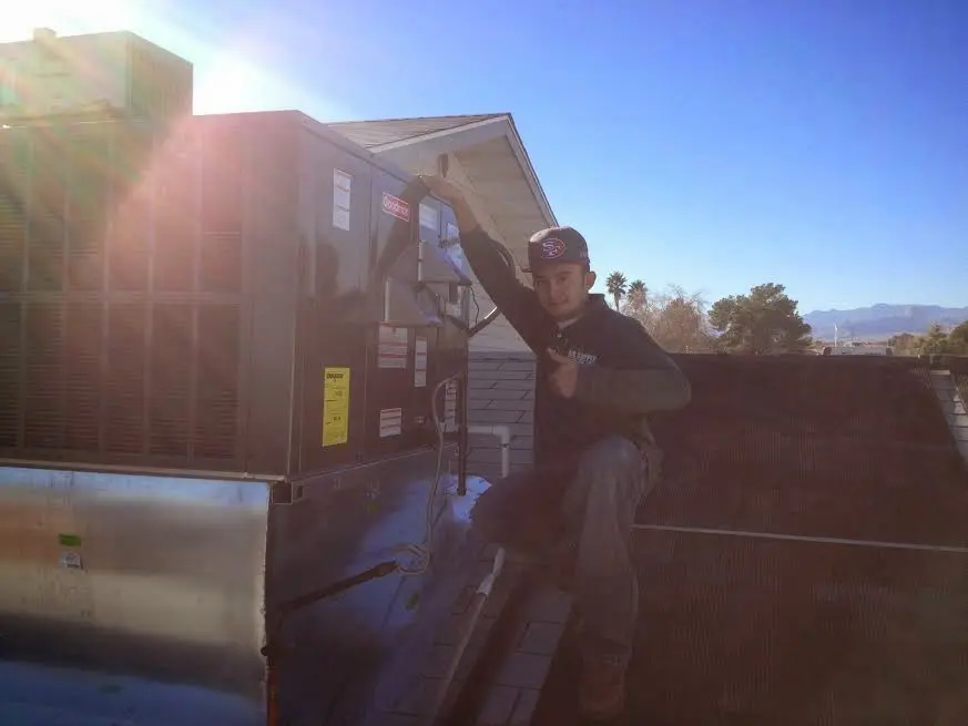 HVAC technician performing Air Duct Cleaning on a rooftop unit in Benton
